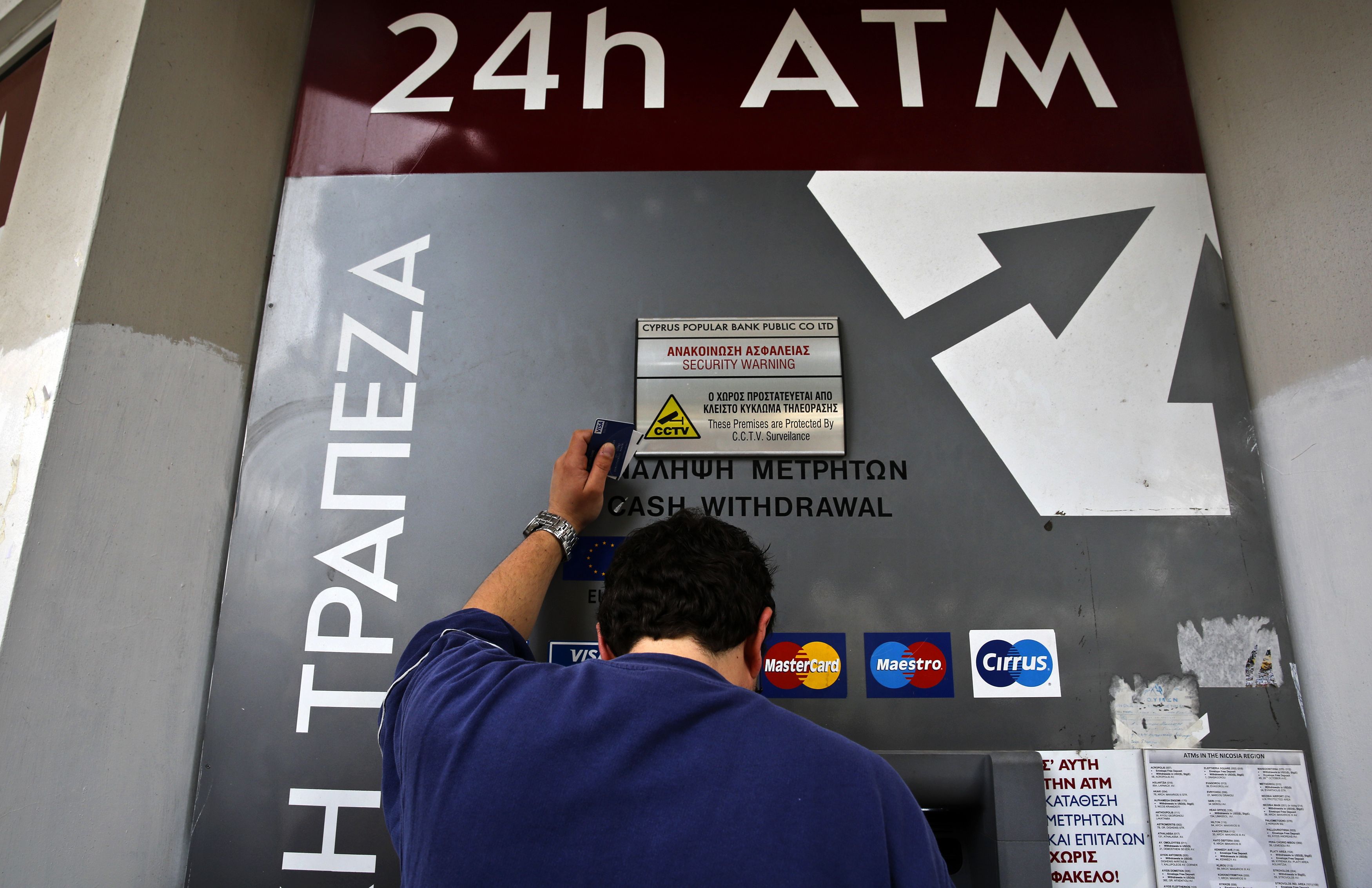 People queue up to make a transaction at an ATM outside a branch of Laiki Bank in Nicosia.