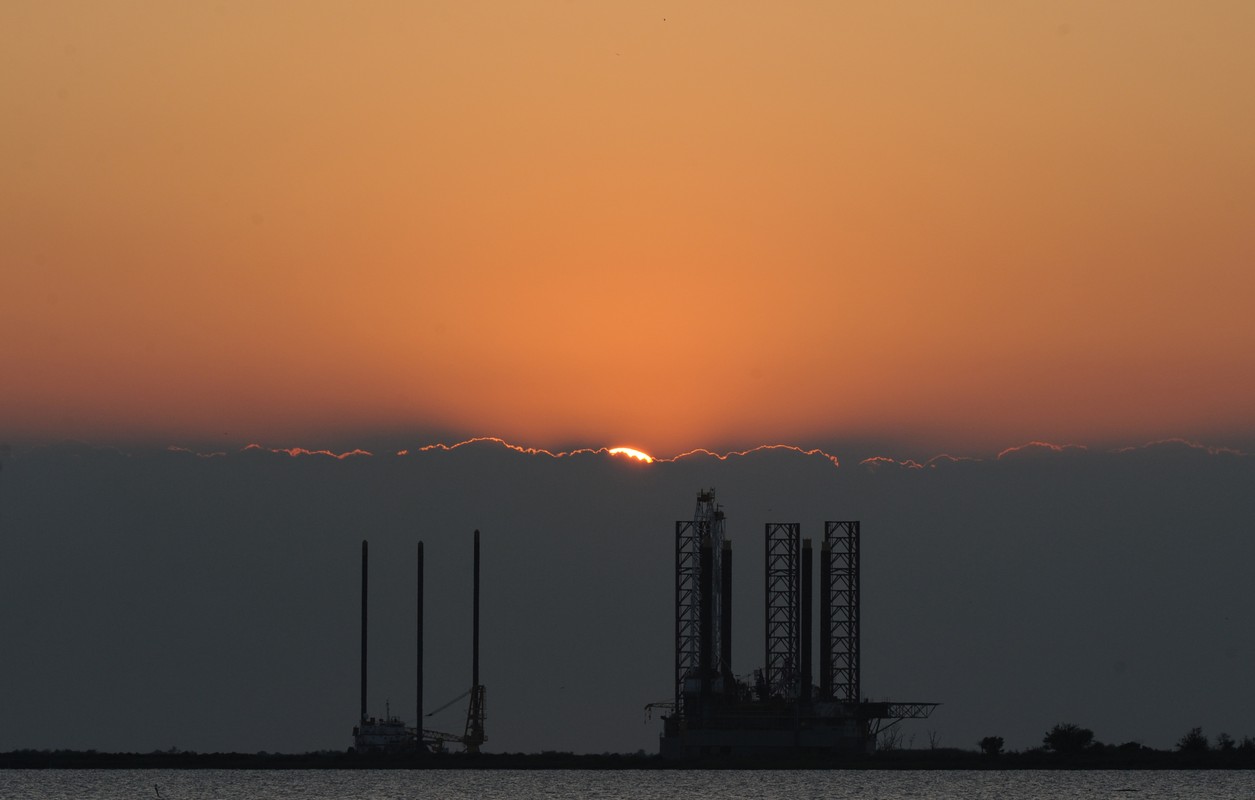 The sun sets over an oil platform waitin