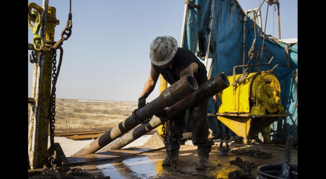 A worker prepares to lift drills by pulley to the main floor of Endeavor Energy Resources LP's Big Dog Drilling Rig 22 in the Permian basin outside of Midland, Texas, U.S., on Friday, Dec. 12, 2014.