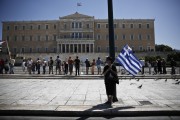 A woman holds a Greek flag with a smaller Cypriot flag attached to it during a May Day rally in front of the parliament in Athens May 1, 2013. REUTERS/Yorgos Karahalis