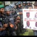A supporter of the #BringBackOurGirls campaign carries a placard showing the missing faces of the kidnapped Chibok schoolgirls as policewomen block supporters of the 219 Chibok schoolgirls kidnapped by Boko Haram militants from marching to the president's official residence in Abuja on October 14, 2014.
