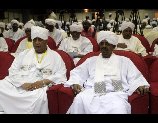 Sudan's President Omar al-Bashir (R) sits before addressing the National Consultative Council in the capital Khartoum on October 21, 2014. Sudan's ruling National Congress Party is to nominate three contenders to be its leader and presidential election candidate, with veteran incumbent Omar al-Bashir on the shortlist. AFP PHOTO/ASHRAF SHAZLY