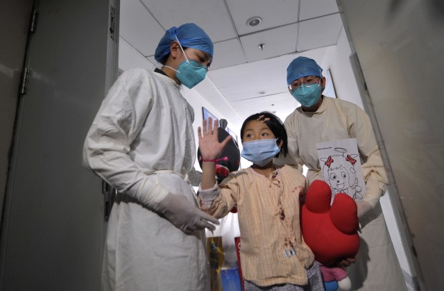 A girl, who was previously infected with the H7N9 bird flu virus, waves as she is being transferred to a public ward from the ICU at Ditan hospital in Beijing, April 15, 2013.(REUTERS/Stringer)