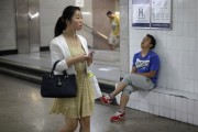 A man sleeps as a woman walks past an entrance to a subway station at an underground passage in central Beijing. Reuters/ Barry Huang