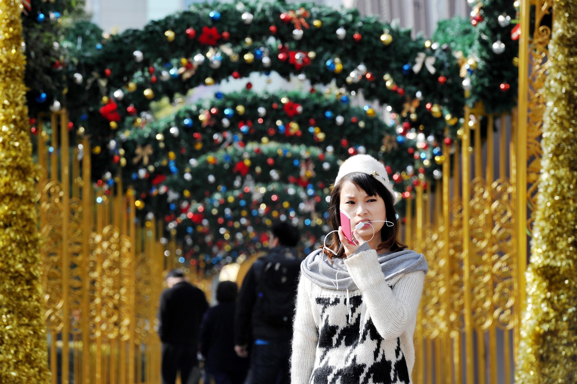 A woman talks on her mobile phone under Christmas decorations displayed outside a shopping mall in Shanghai. AFP/ Getty / Philippe Lopez