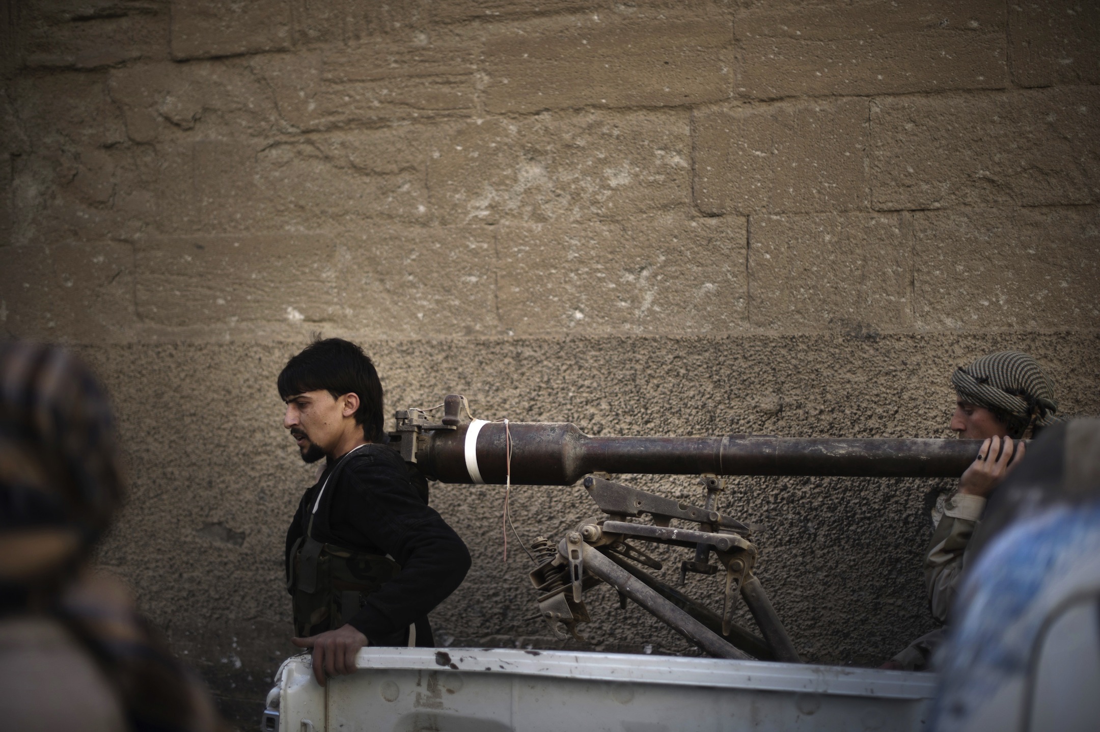 Rebels fighters carry a portable canon during fighting against Syrian government forces on February 27, 2024 in the Hawiqah neighbourhood of the eastern Syrian town of Deir Ezzor.