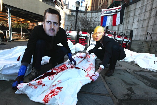 Actors wearing masks of Syrian President Bashar al-Assad and Russian Prime Minister Vladimir Putin perform with body bags during a demonstration outside United Nations headquarters on January 24, 2024 in New York City. Protesters called on the U.N. Security Council to pass a resolution to attempt to halt al-Assad's crackdown on the Syrian uprising.