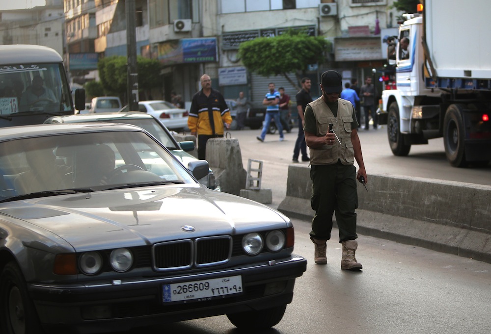 A Hezbollah militant checks cars for bombs and explosives in Beirut on September 23, 2013. (AFP PHOTO/JOSEPH EID)