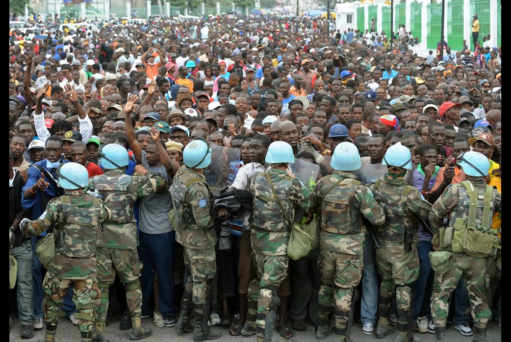 UN peacekeepers try and control Haitians queueing for aid at a distribution point outside the Presidential palace in Port-au-Prince on January 25, 2010.