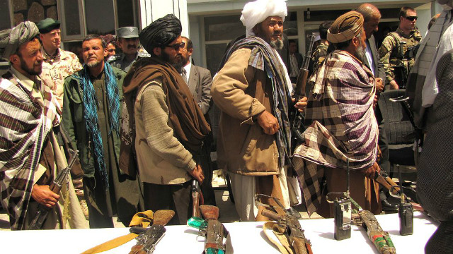 Former Taliban fighters line up to hand over their rifles to representatives of the Afghan government. (Source: FutureTrillionaire/Wikimedia Commons)