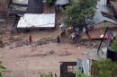 People stand next to damaged homes after a landslide caused by heavy rains came down on a low income neighborhood in the city of Chilpancingo, Mexico, Monday Sept. 16, 2013.