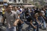 Palestinian demonstrators throw stones towards Palestinian police during a protest near the municipality building in the West Bank city of Hebron, Monday, Sept. 10, 2012. 