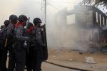 FILE - In this Thursday, March 21, 2024 file photo, armed Myanmar police officers provide security around a smoldering building following ethnic unrest between Buddhists and Muslims in Meikhtila, Mandalay division, about 550 kilometers (340 miles) north of Yangon, Myanmar.
