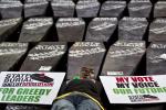 In this Wednesday, Jan. 16, 2013 file photo, a demonstrator lies on mock coffins on which are written "State Burial, Ballot Revolution", before the coffins were carried to the Parliament and set on fire to protest against an attempt by Members of Parliament (MPs) to award themselves a $110,000 bonus, which was later vetoed by the president, in Nairobi, Kenya.