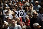 A protestor walks holding a banner reading 'No' during a demonstration against regional government imposed austerity plans to restructure and part privatize the health care sector in Madrid, Sunday, April 21, 2013.