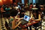 Three young Vietnamese girls use a laptop and smart phones to go online at a cafe in Hanoi, Vietnam Wednesday, May 14, 2013.
