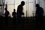 In this Tuesday, May 14, 2024 photo, workers are silhouetted at a construction site of a residential project in Rizhao city in east China's Shandong province.