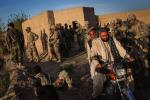Local Afghan men ride their motorcycle past soldiers with the Afghan National Civil Order Police during a two-day, joint mission with the United States Army's 3rd Battalion, 41st Infantry Regiment near Command Outpost Siah Choy on March 25, 2024 in Kandahar Province, Zhari District, Afghanistan.