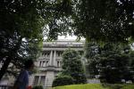 A man looks up as he walks past the Bank of Japan headquarters in Tokyo July 5, 2013. The Bank of Japan is expected to keep monetary policy on hold at a review next week while presenting a more upbeat view of the economy, based on growing signs that positive effects are rippling through from the government's reflationary strategy.