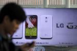A man uses his mobile phone near a banner advertising LG Electronics' G2 smartphone at downtown Seoul, South Korea, Thursday, Oct. 24, 2013.