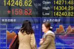 Pedestrians walk past a share prices board in Tokyo on November 11, 2013.