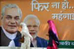 Pedestrians pass an election poster featuring Narendra Modi (right) and former prime minister Atal Behari Vajpayee in New Delhi on April 5, 2014.