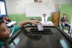 An Egyptian child puts the ballot paper in the ballot box for his father in a polling station in the Cairo suburb of Imbaba on May 27, 2024 in Cairo, Egypt. 