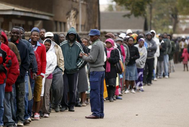 A police officer keeps watch as Zimbabweans wait to cast their vote in Mbare township outside Harare July 31, 2013. A police officer keeps watch as Zimbabweans wait to cast their vote in Mbare township outside Harare July 31, 2013.