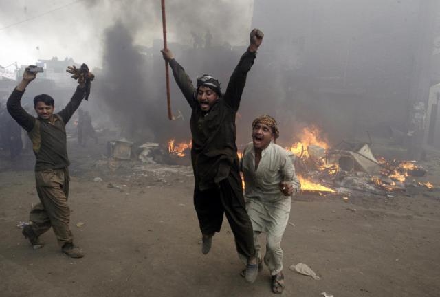 Pakistani men, part of an angry mob, react after burning belongings of Christian families, in Lahore, Pakistan, Saturday, March 9, 2013. 
