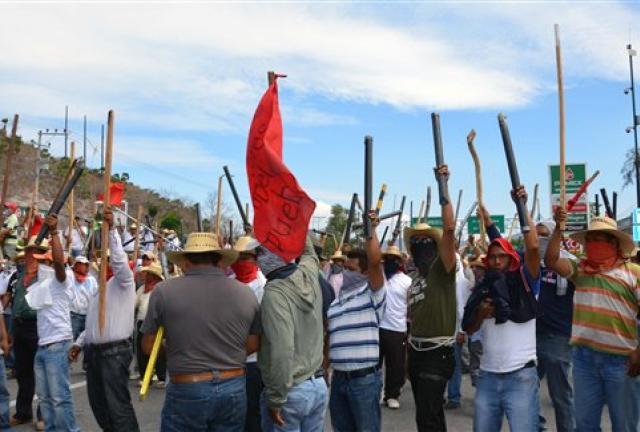 Teachers chant slogans holding up metal pipes and wooden sticks while blocking a major highway in Chilpancingo, Mexico, Thursday, April 11, 2013. The teachers, who are protesting an educational reform that will submit them to evaluation and loosen union control over hiring and firing, left peacefully after negotiating with police. (AP Photo/Alejandrino Gonzalez)