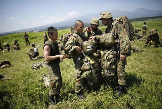 Japanese Ground Self-Defense Force's 1st Airborne Brigade soldiers carry parachutes for parachute drop training during their military drill at Higashifuji training field in Susono, west of Tokyo, July 8, 2013. 