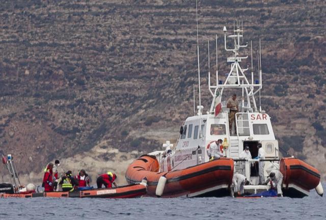 Italian Coast Guard personnel recover a body bag on their patrol boat in Lampedusa island, Italy, Tuesday, Oct. 8, 2013.
