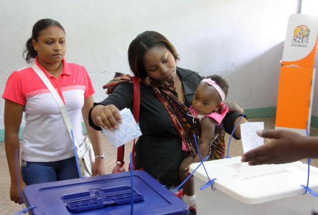 A woman holding her baby casts her vote, during municipal elections held in the city of Maputo, Mozambique, Wednesday, Nov. 20, 2013.