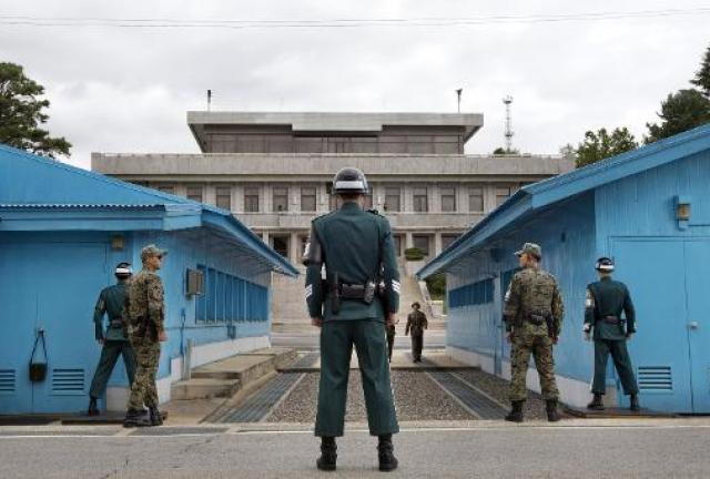 South Korean soldiers (foreground) look toward the North Korean side (back) as a North Korean soldier (centre R, back) approaches the UN truce village building that sits on the border of the Demilitarized Zone in Panmunjom on September 30, 2013. South Korean soldiers (foreground) look toward the North Korean side (back) as a North Korean soldier (centre R, back) approaches the UN truce village building that sits on the border of the Demilitarized Zone in Panmunjom on September 30, 2013.