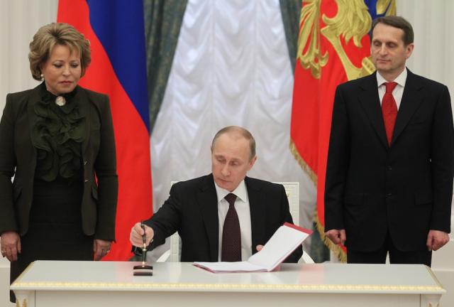 MOSCOW, RUSSIA - MARCH 21: Russian President Vladimir Putin flanked by Upper House Speaker Valentina Matviyenko (L) and State Duma Speacker Sergei Naryshkin (R) signs final decree completing annexation of Crimea at the Kremlin on March 21, 2024 in Moscow, Russia. Putin completed the legal process of making Crimea part of Russia. Credit Sasha Mordovets/Getty Images