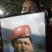 A supporter of Venezuela's President Hugo Chavez cries as she holds a picture of Venezuela's late President Hugo Chavez, as Chavistas gather in Bolivar square to mourn Chavez's death in Caracas, Venezuela, Tuesday, March 5, 2013.