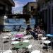 In this Saturday, April 20, 2013, photo, people sit at a coffee shop in front of a barrier in front of the UN-controlled buffer zone in Cyprus' divided capital Nicosia. 